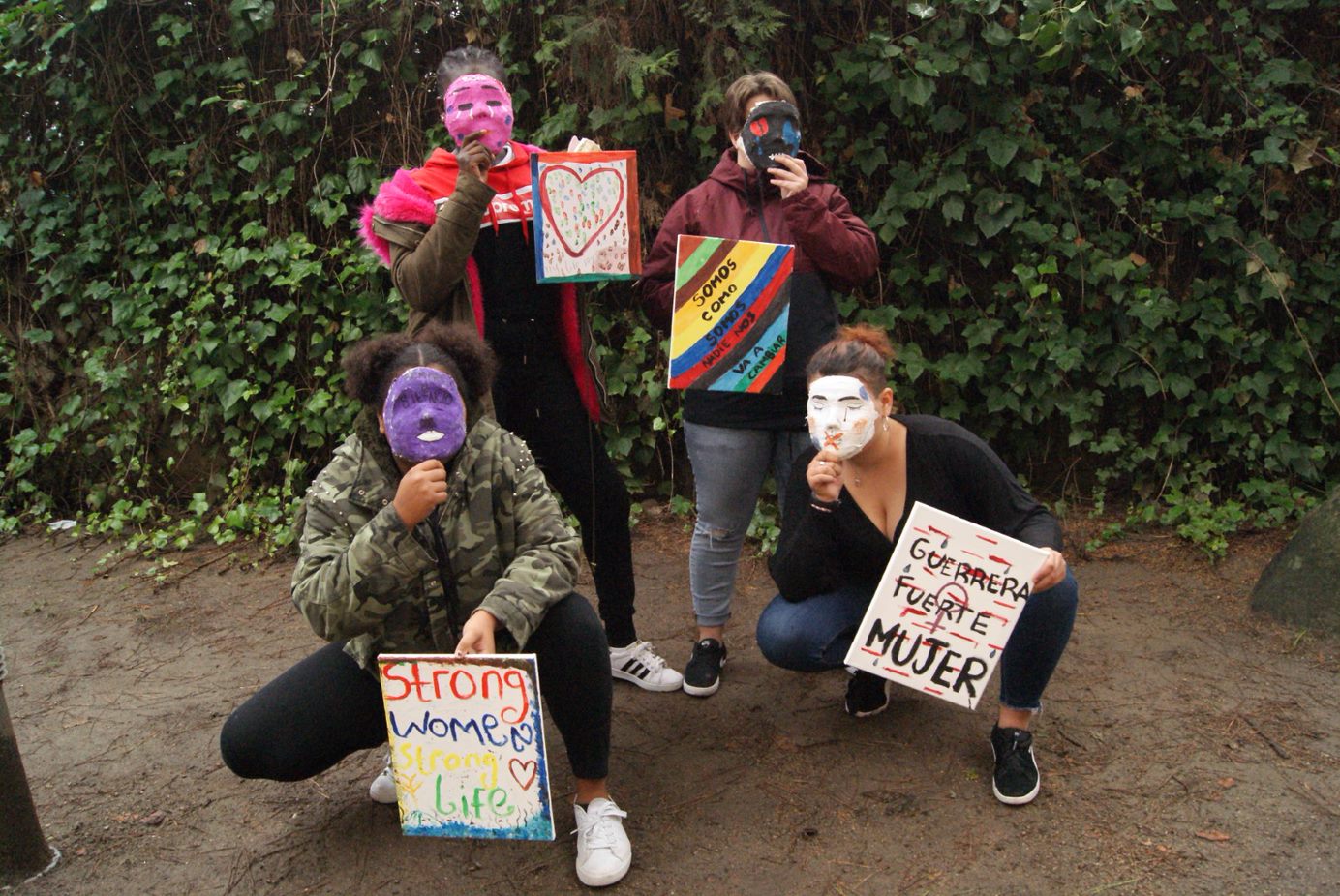 Quatre dones o joves del Projecte Claudel amb màscares i pintures que han fet denunciant la violència masclista.