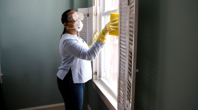senyora racialitzada neteja els vidres d'una casa